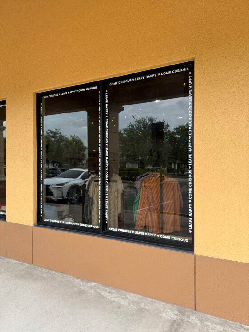 Clothing store window display with orange wall