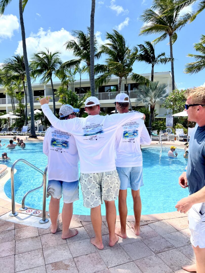 Three people in matching shirts beside pool